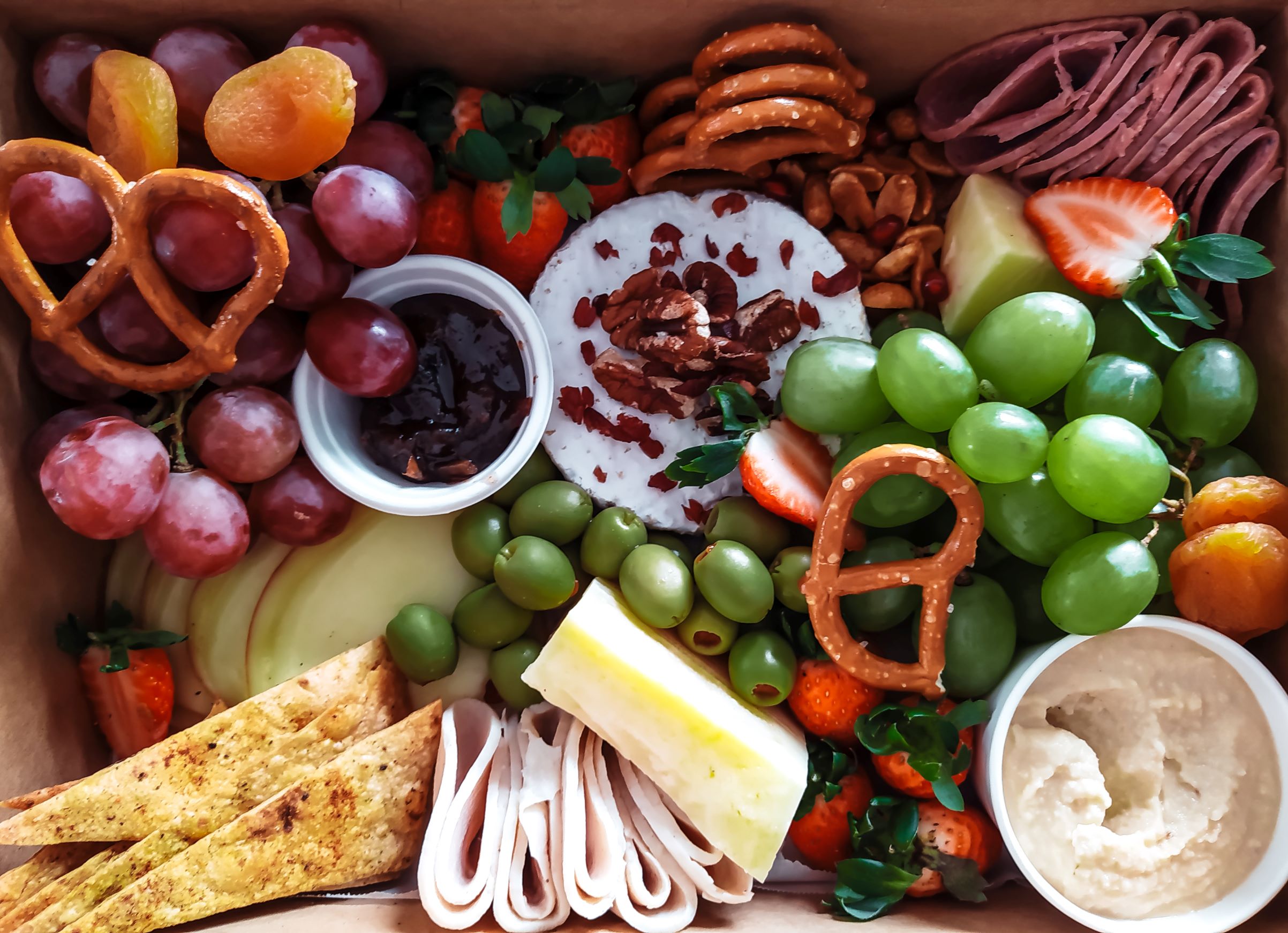 food platter with pretzels, fruit, deli meat, and cheese