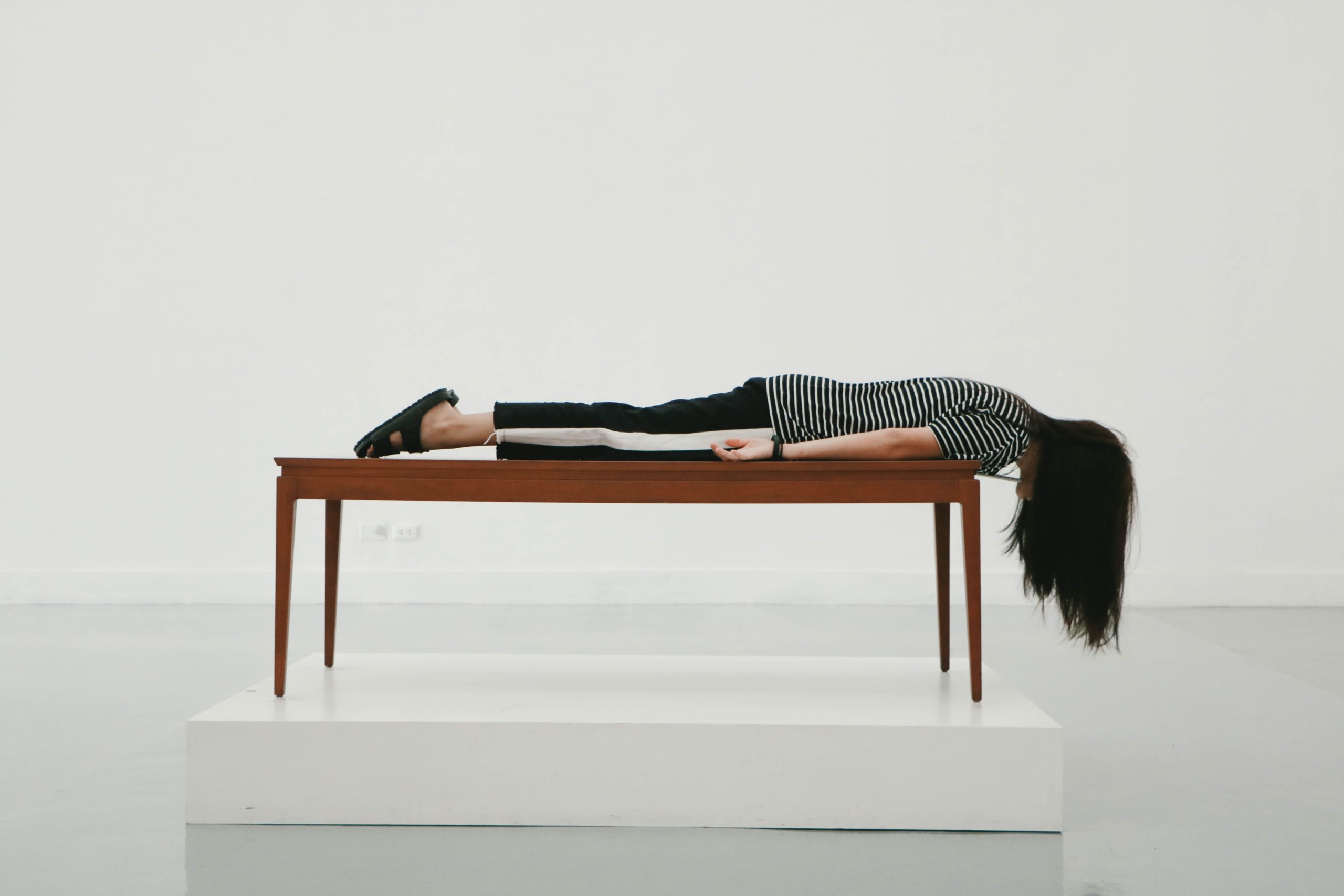 A woman lies facedown on a table to represent an exhausted student during finals week.